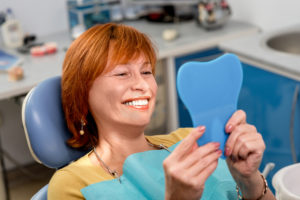 A woman looking at her teeth in a mirror | quality dental care